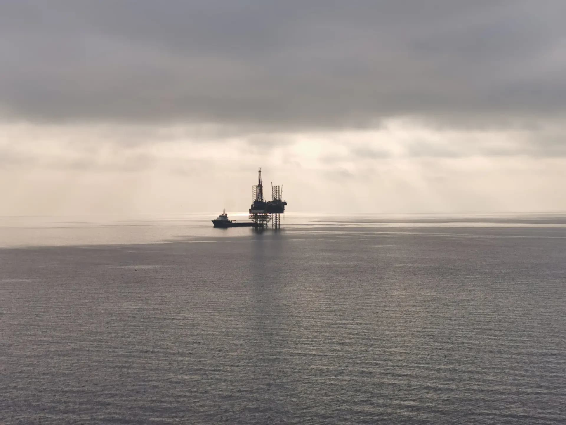 Offshore rig silhouetted under a moody overcast sky